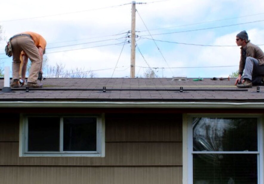 John Hooker and Mike Loesch begin installation of solar panels on the roof of a Columbia, Missouri, home.