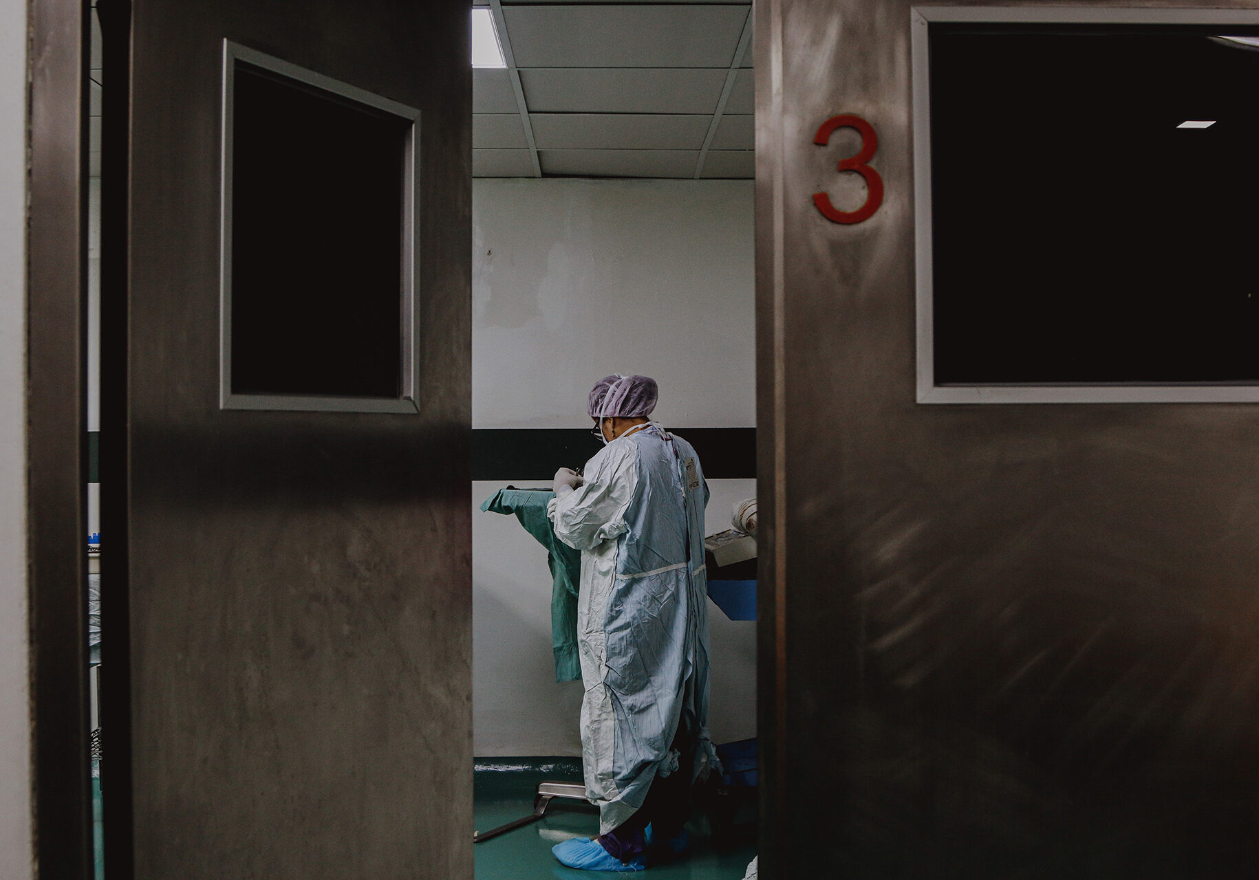 A photo frames a hospital hallway, as a health care worker in their gown looks down with their back facing the camera. This image accompanies the Flatland guide on what to know about the evolving standards of care in hospital systems and health care clinics.