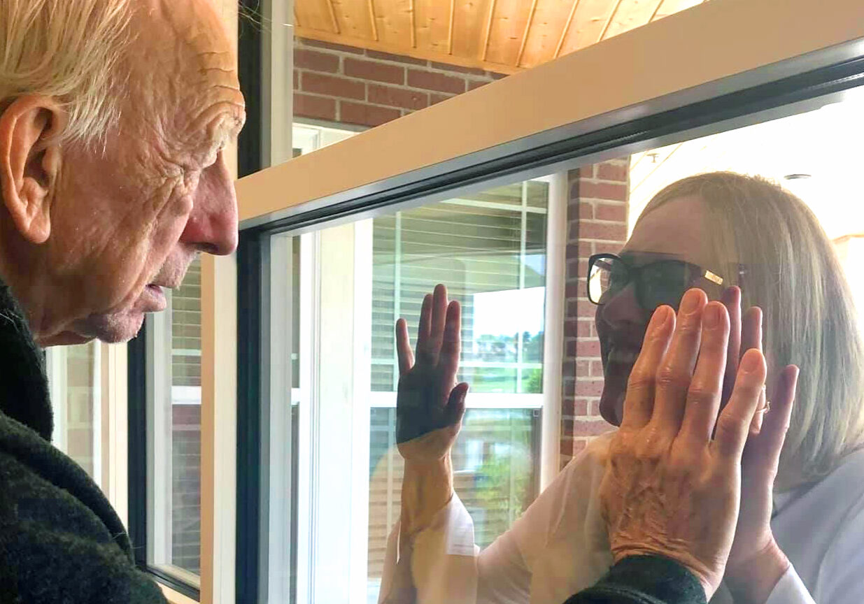 An unidentified family member visits through the window with their loved one at Cross Creek.