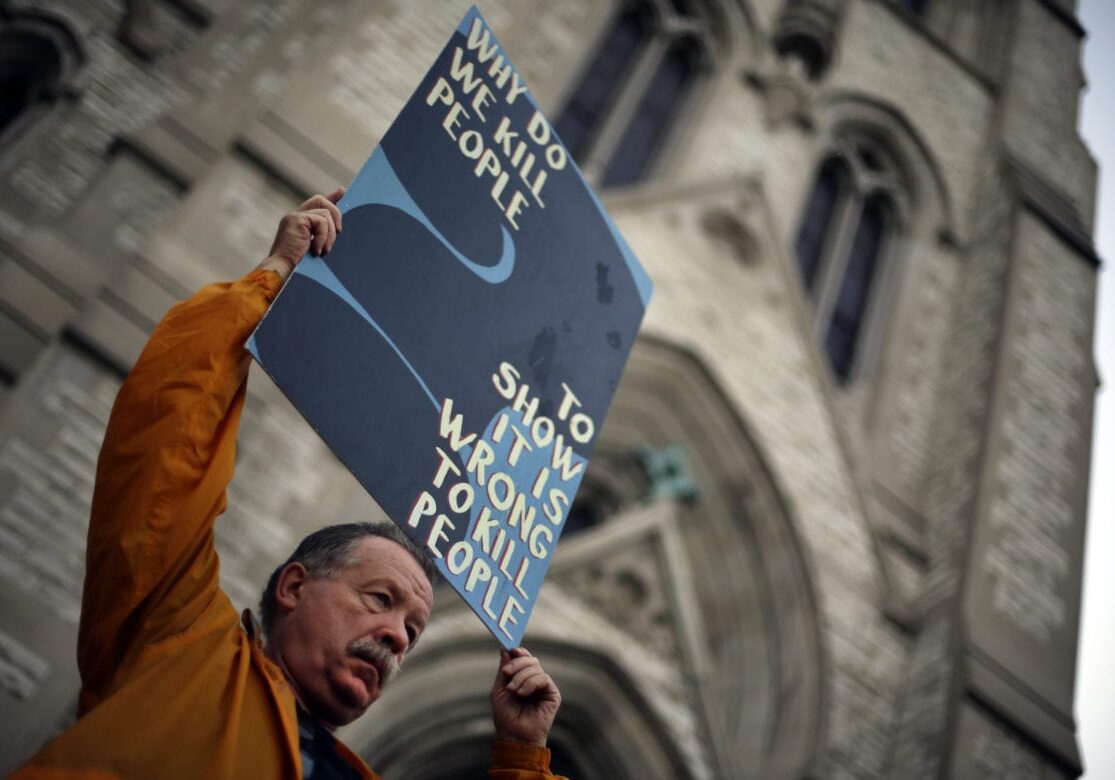 Death penalty opponent Herve Deschamps holds a sign over his head during a vigil outside St. Francis Xavier College Church hours before the scheduled execution of Missouri death row inmate Russell Bucklew, Tuesday, May 20, 2014, in St. Louis. A federal appeals court panel granted a temporary halt to the execution of Bucklew on Tuesday evening citing concerns that he could suffer during lethal injection due to a rare medical condition. The panel's ruling could be overturned by the full appeals court, or by the U.S. Supreme Court. (AP Photo/Jeff Roberson)