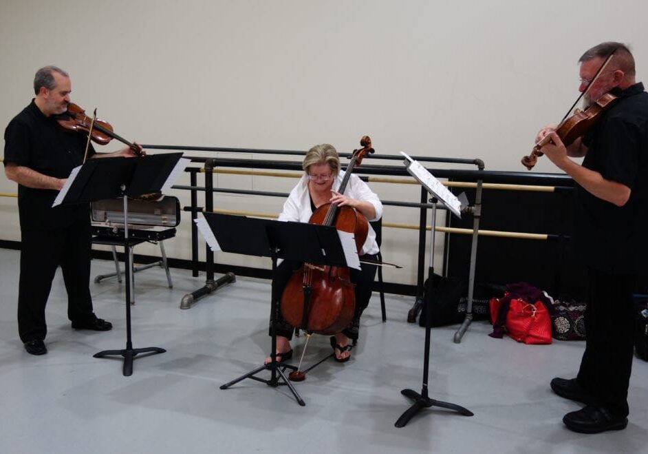 Three people playing string instruments.