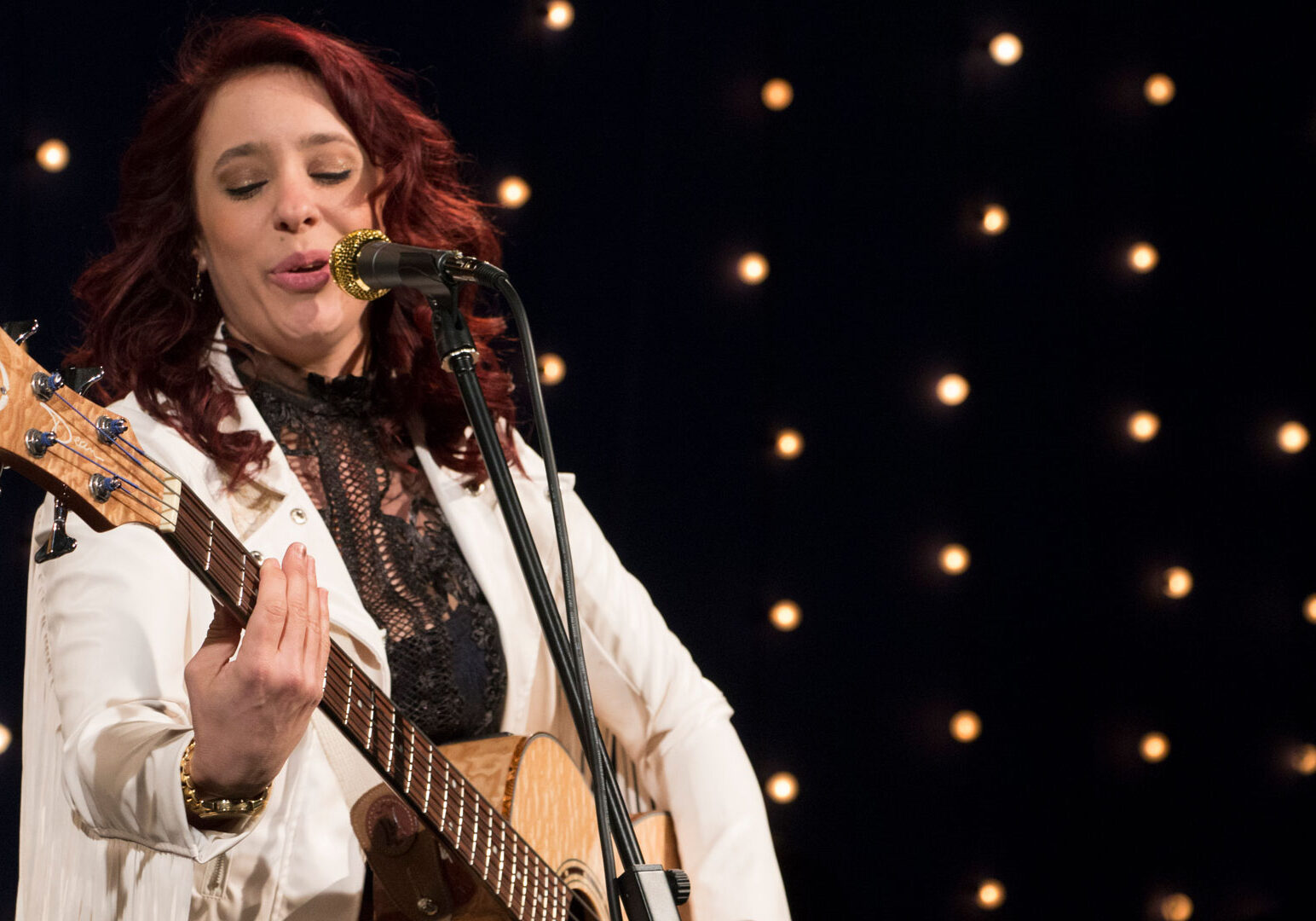 Danielle Nicole plays the guitar and sings into a mic.