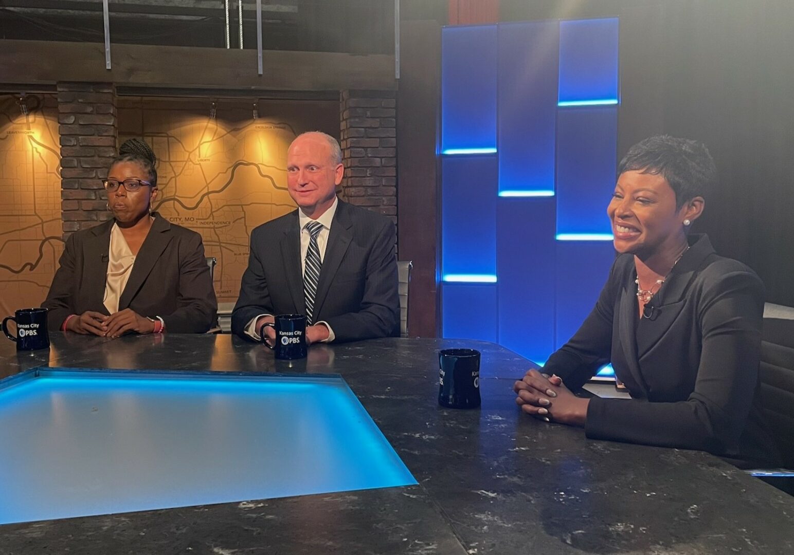 Three people seated at a table. Week in Review set.