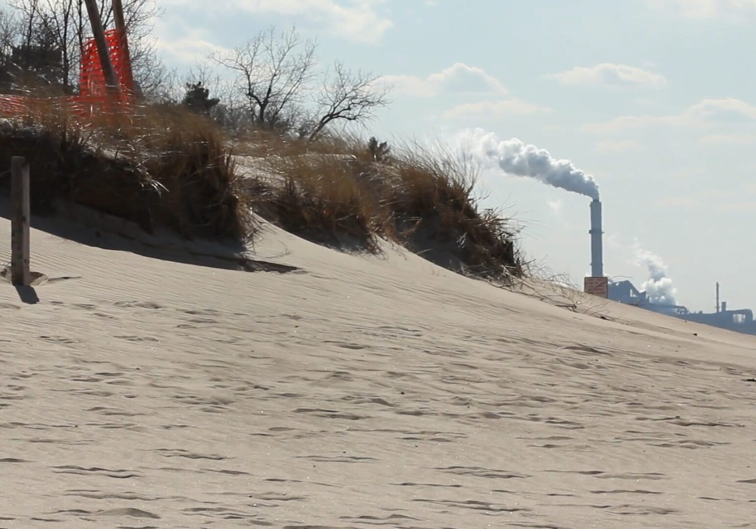 A beach with a visible smokestack in the background