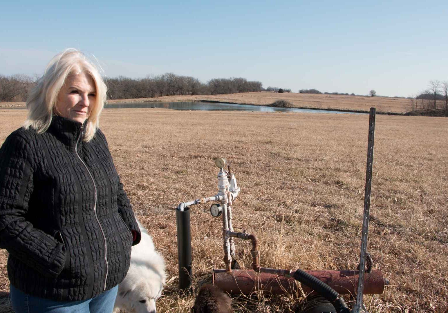 Connie Mayberry stands next to a gas well that roughly marks where development would begin behind her property.