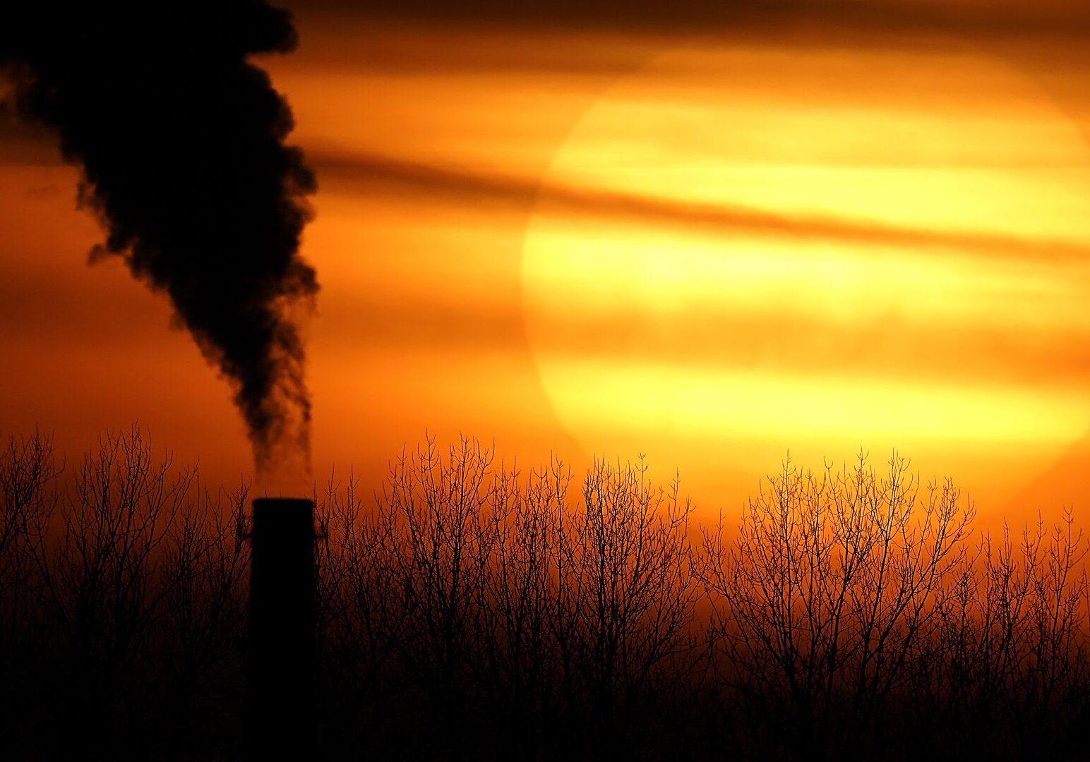 In this Feb. 1, 2021, a smokestack from Evergy's Hawthorn coal-fired power plant is silhouetted against the setting sun in Kansas City.