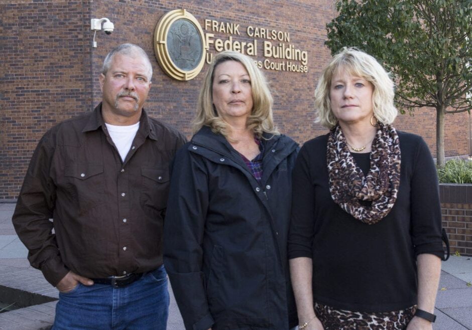 One man and two women standing outside a court house.