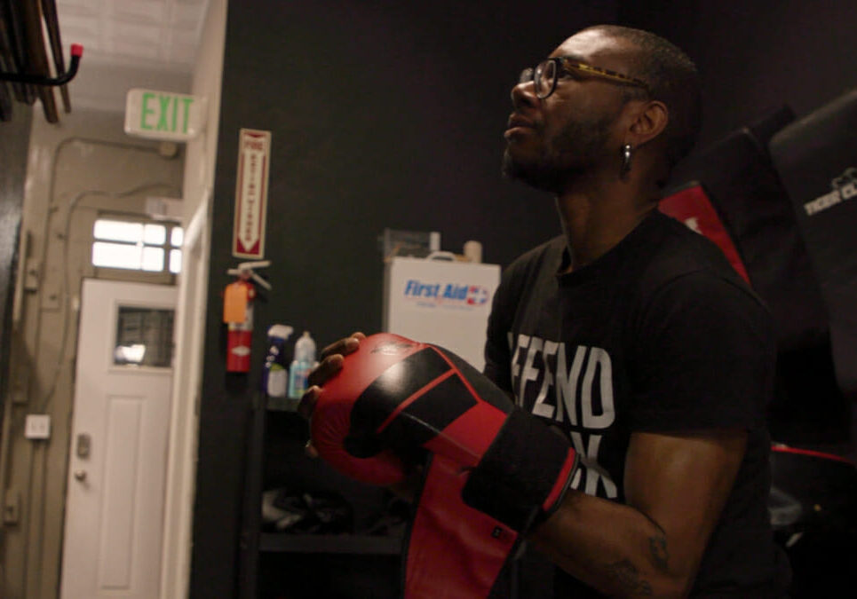 Person in glasses with boxing gloves in dark room