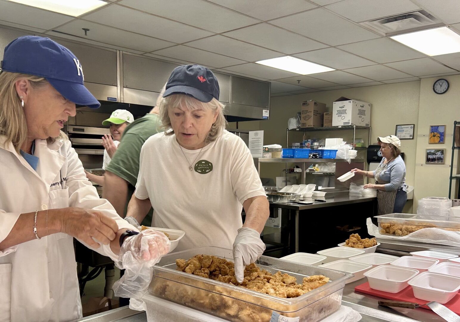 Volunteers scoop meat into containers in the kitchen of Pete’s Garden.