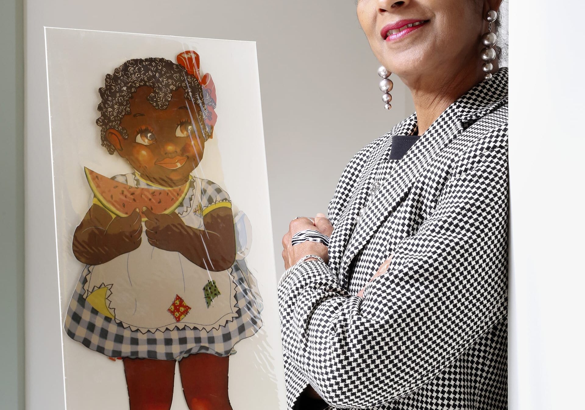 This photo shows Arabella Grayson standing next to her private collection of African American paper dolls.