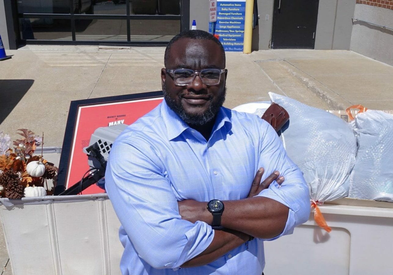 Funmi Popoola, President and CEO of Goodwill of Western Missouri & Eastern Kansas, leans against carts filled with donations.