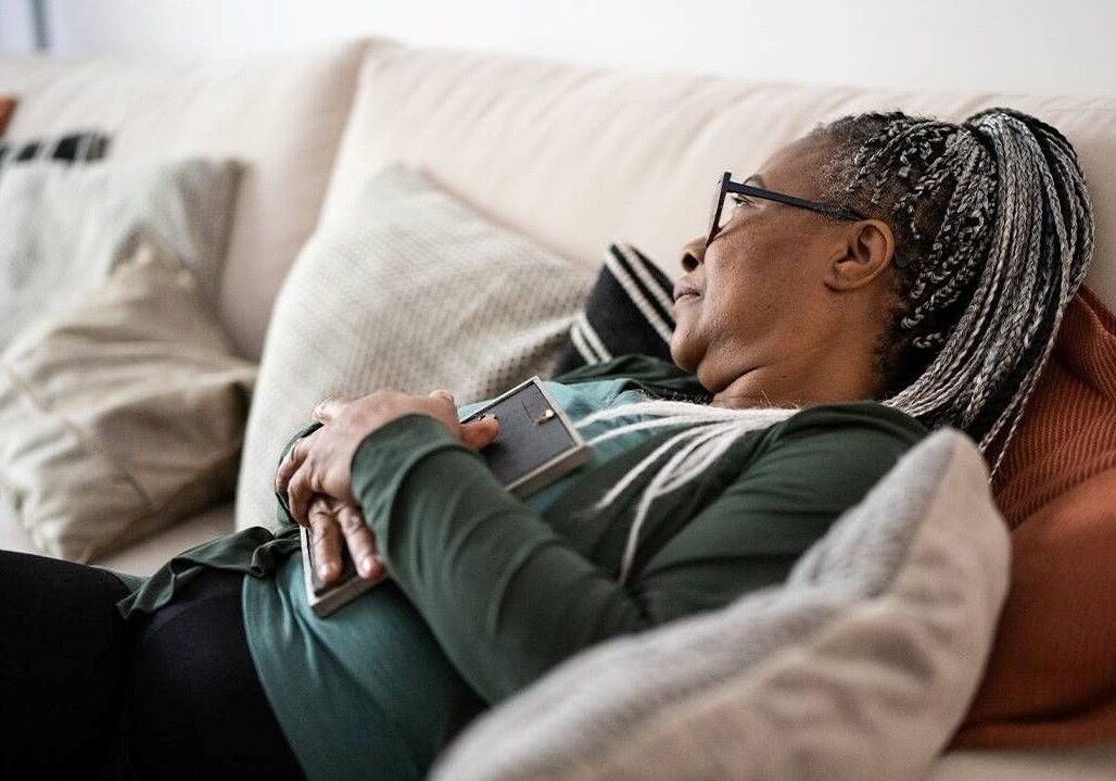 Photo illustration of a woman on a couch, gazing into the distance.