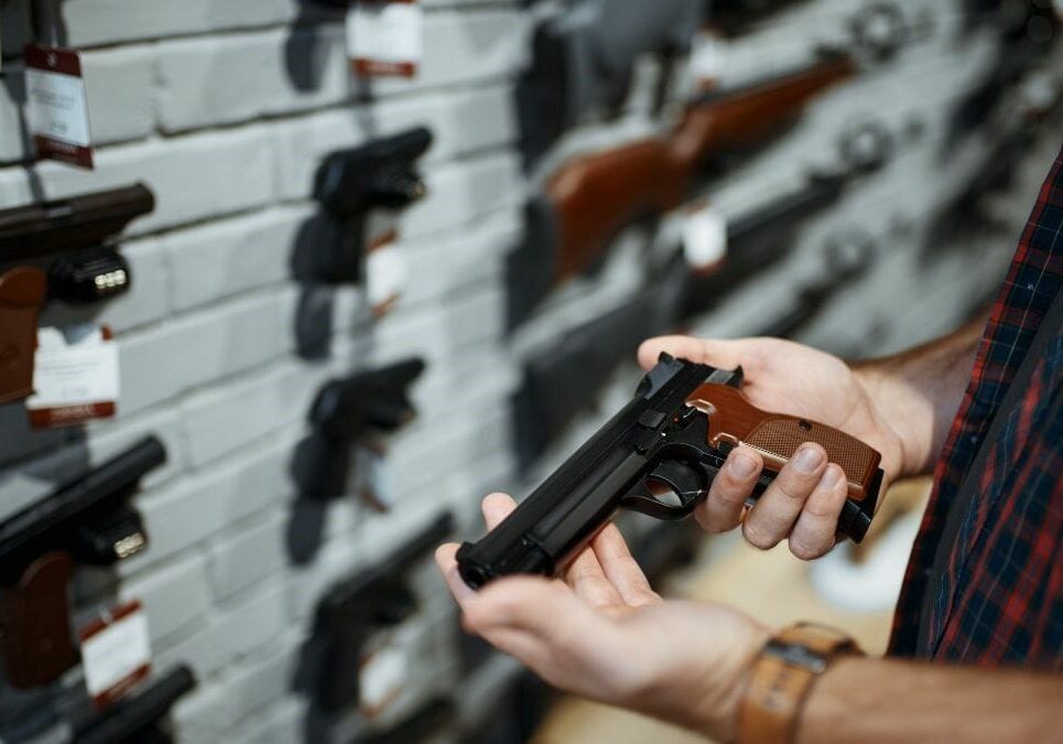 A man holds a handgun in a store.