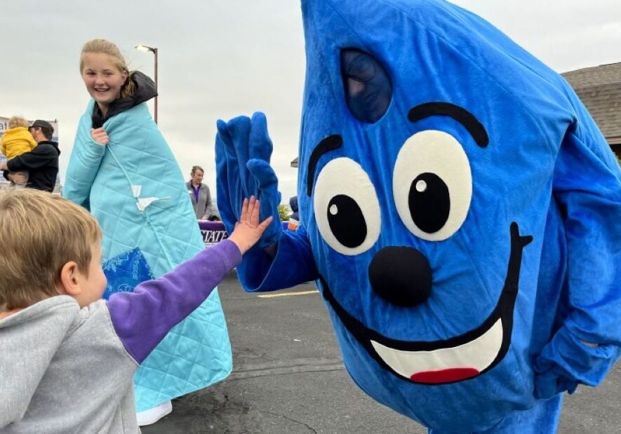 The Hays water conservation program's mascot, WaterSmart Wally, gives out high fives at a recent street fair. Wally is just one sign of how far the town's water-saving culture has come since the 1990s.