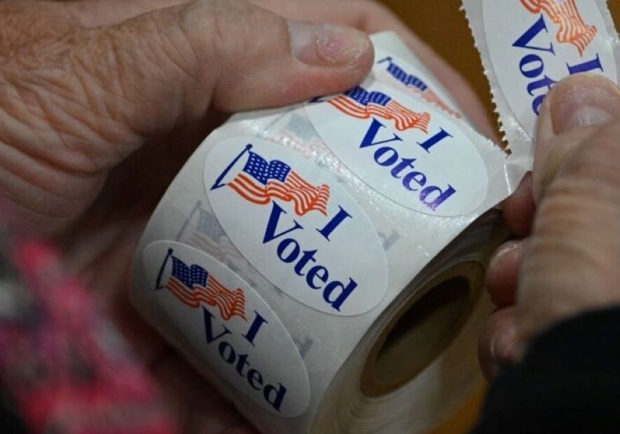 A poll worker peels off an "I Voted" sticker.