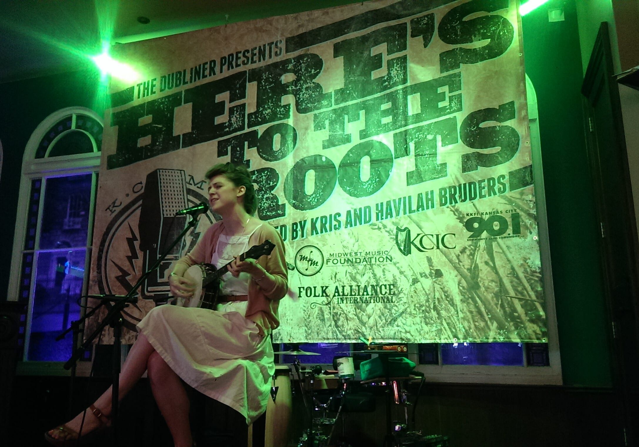 A woman sits with her guitar.