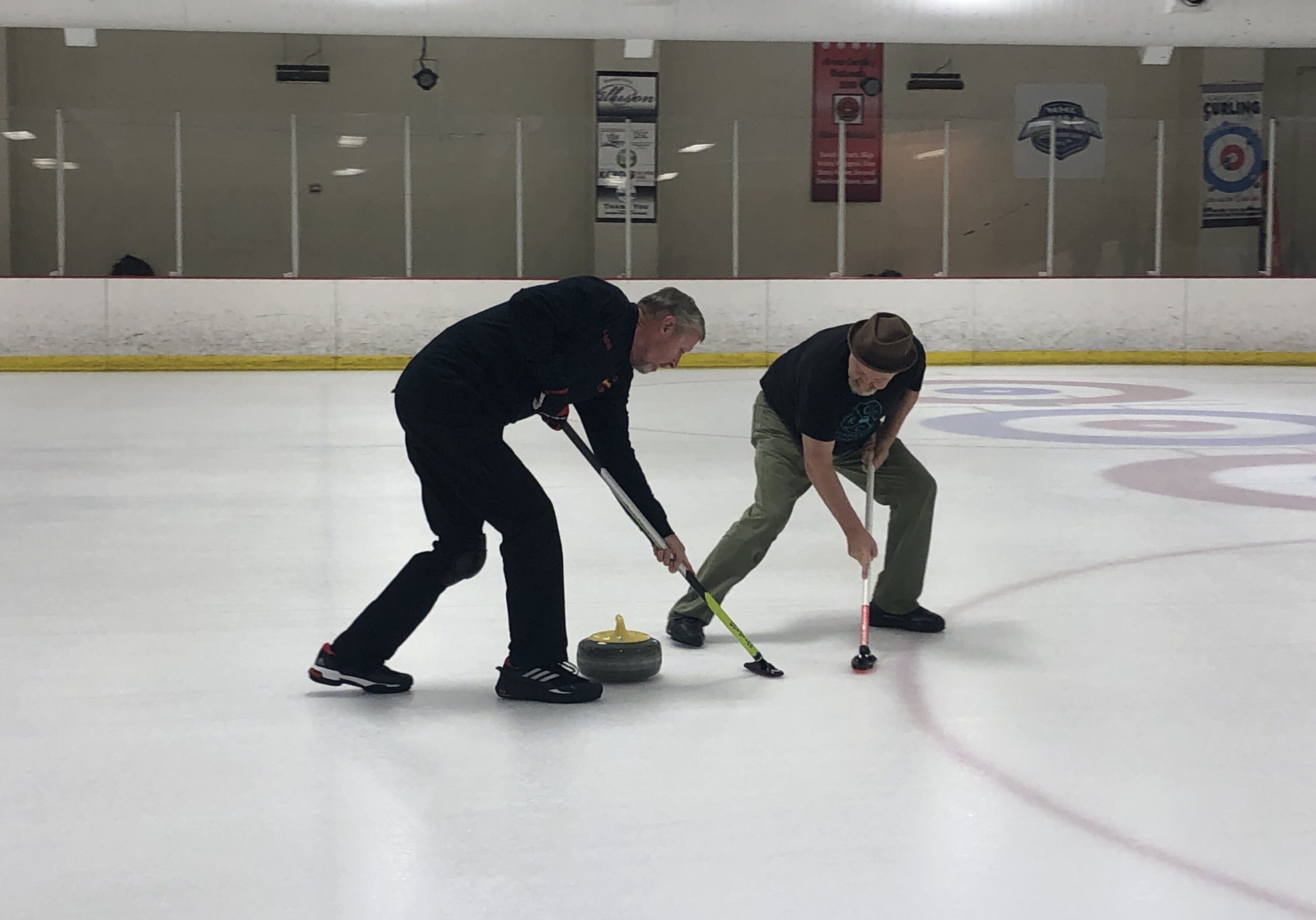 A pair of curlers sweep in front of the stone.