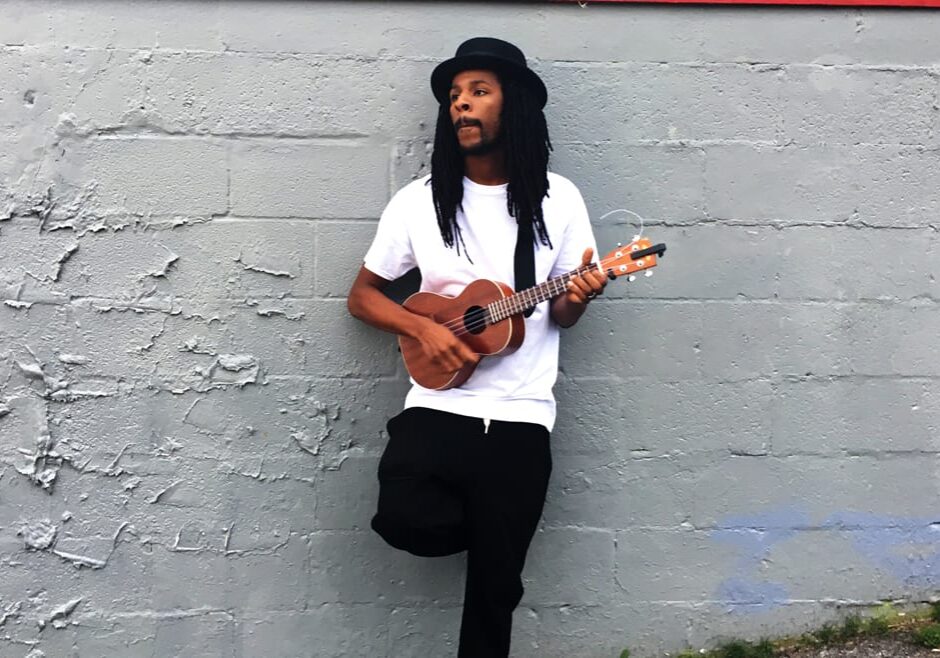 Man standing against wall with ukulele