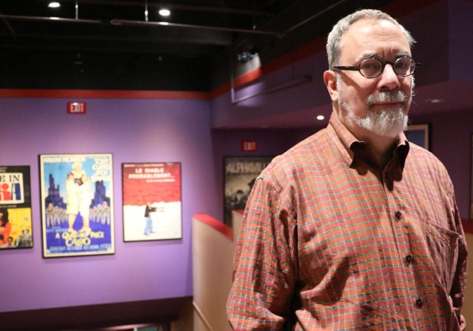 Man stands next to vintage movie posters.