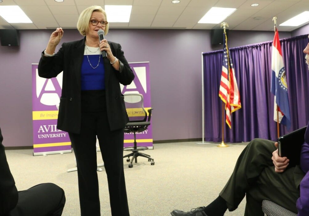 Woman speaks to crowd in conference room.