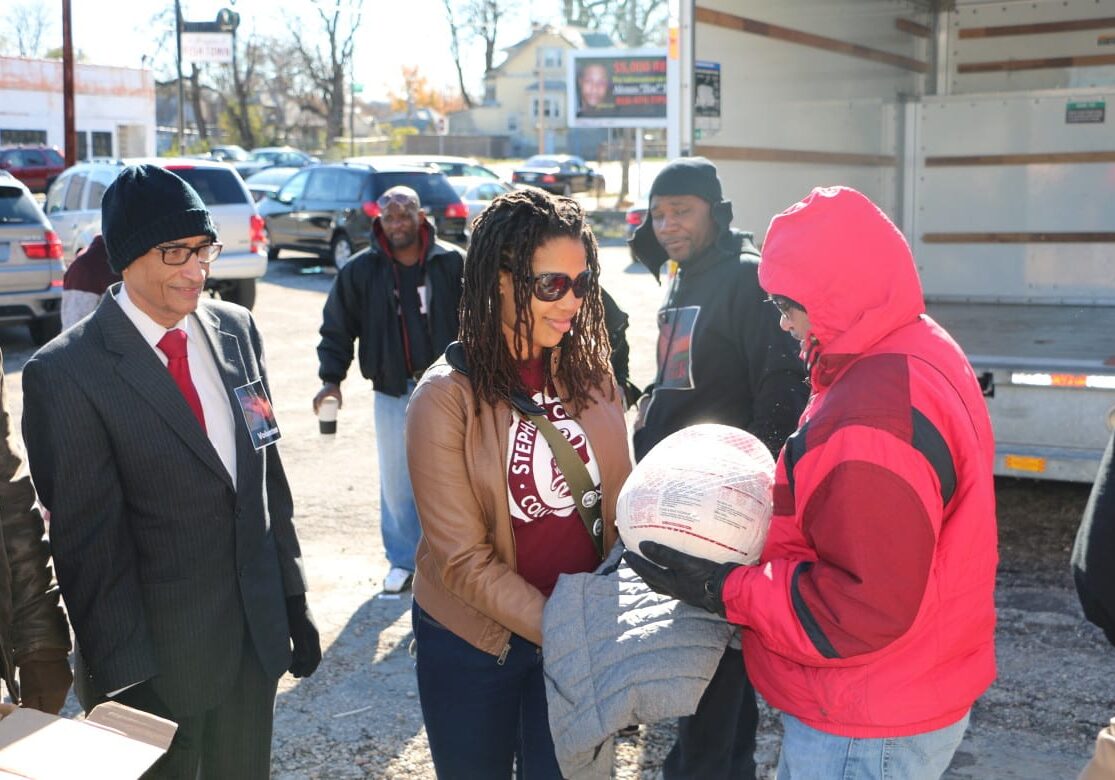 Tanvir Moneem, right, and Dr. Iftekhar Ahmed, far left, distribute a free turkey to a community member last Saturday as part of Crescent Peace, which has organized the free turkey giveaway for four years. (Photo: Daniel Boothe | Flatland)