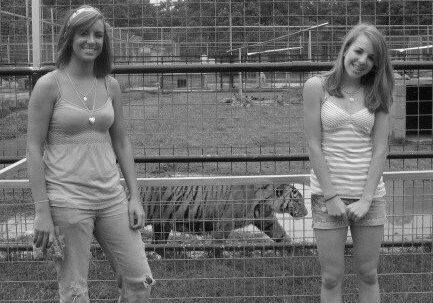 Karr and her sister pose infront of a pacing tiger in a cage.