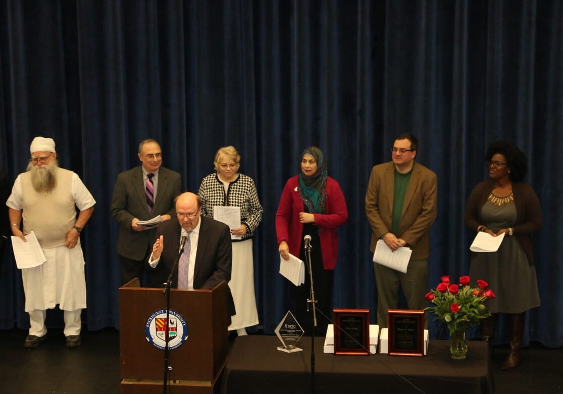 Rev. Dr. Robert Lee Hill at the microphone introduces leaders from various religions in the Kansas City community, including Jewish, Muslim, Baha'I and the Sikh faiths. Everyone came together at Rockhurst University for an interfaith ceremony to honor Martin Luther King's life and work. (Photo: Daniel Boothe | Flatland) 