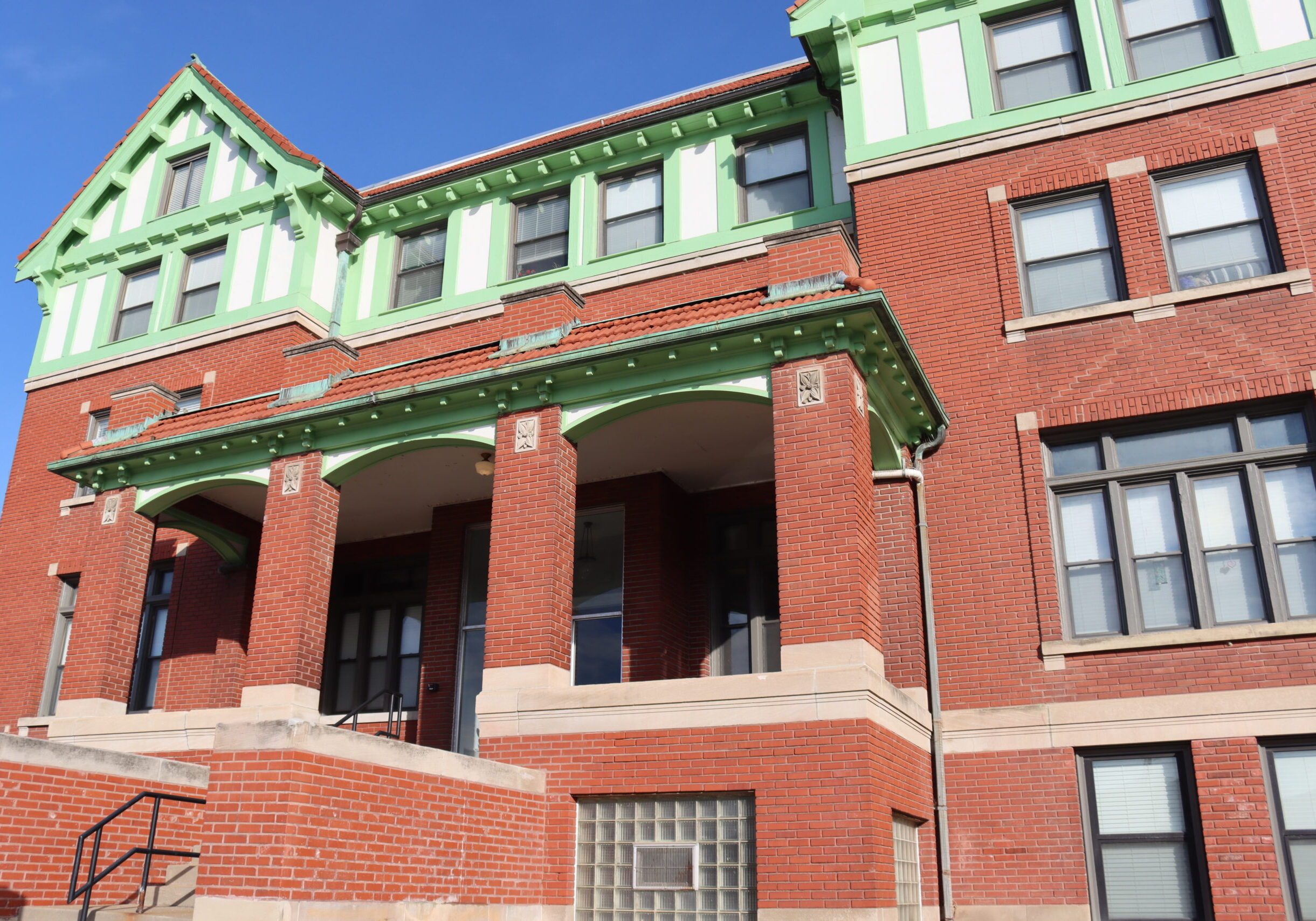 A brick building with Tudor styling and green trim on top.