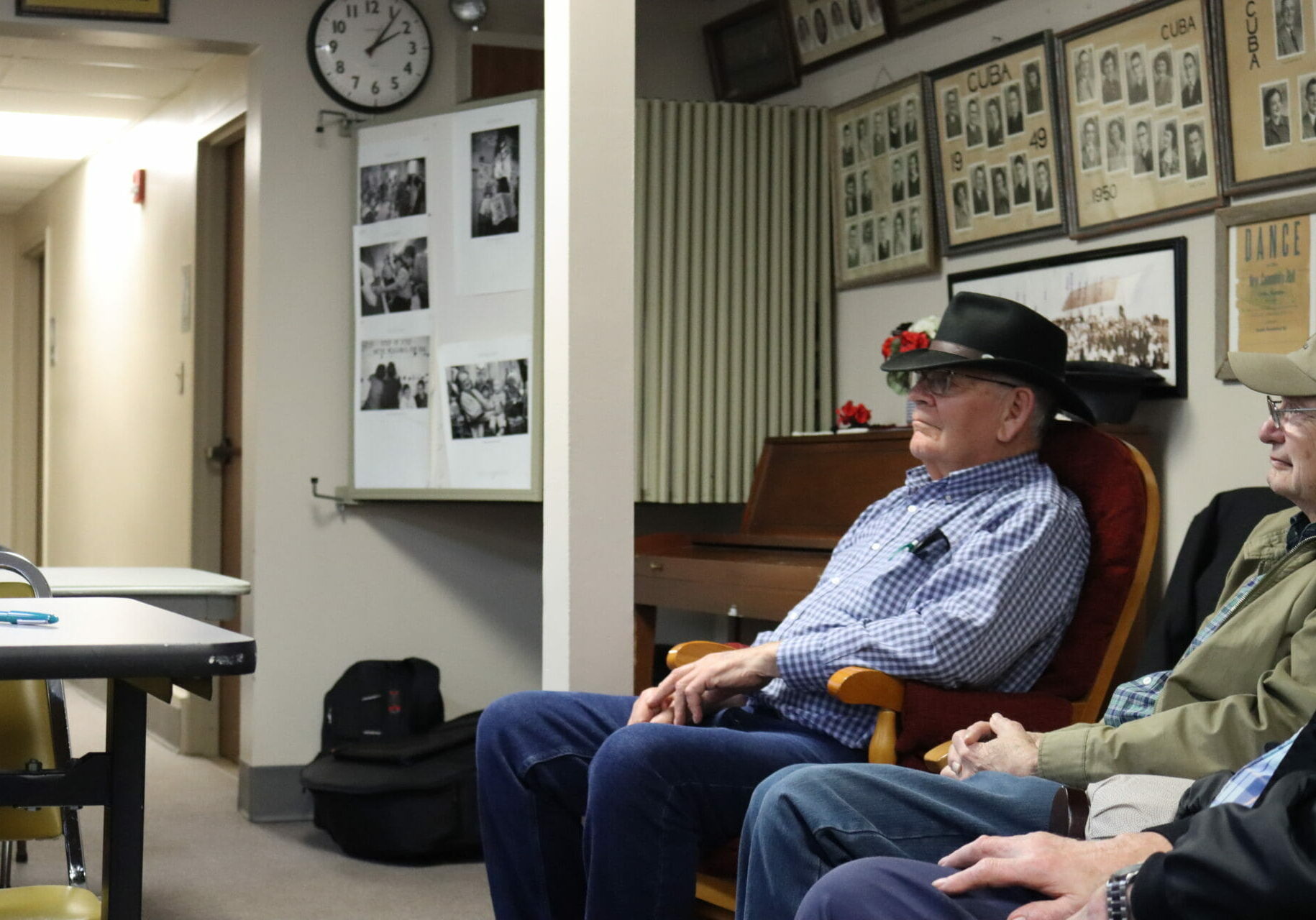 A man in a black cowboy hat sits in a rocking chair.