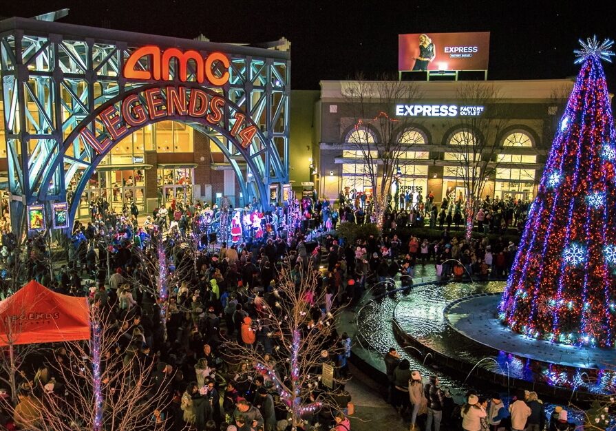 A crowd surrounding a lit Christmas tree at Legends.