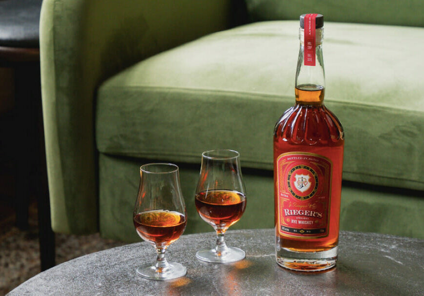 Two glasses and a bottle of J. Rieger & Co.'s Straight Rye Whiskey.