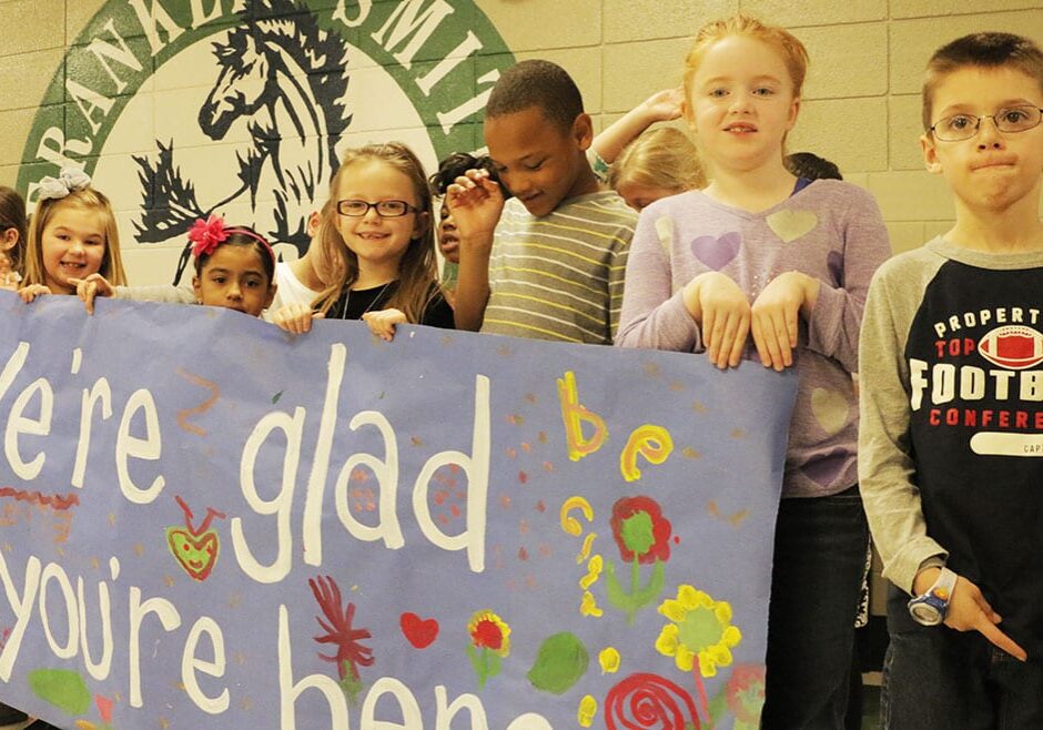 Franklin Smith kids welcoming visitors with a banner