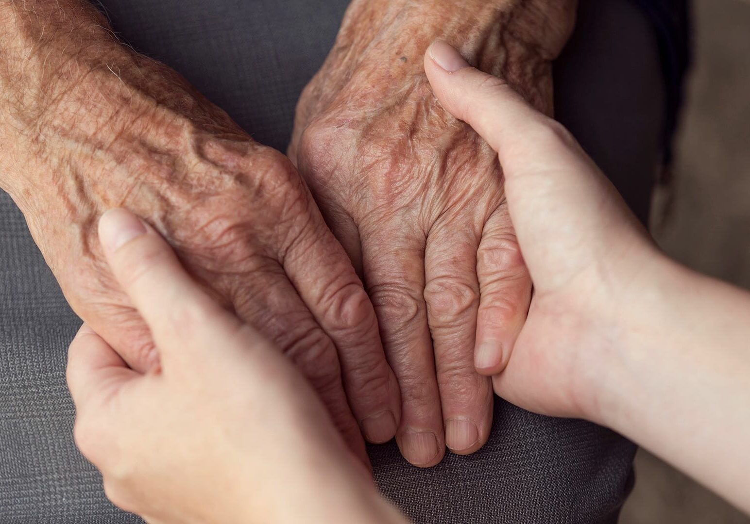 An older adult and a younger person holding hands as they consider long-term care options.