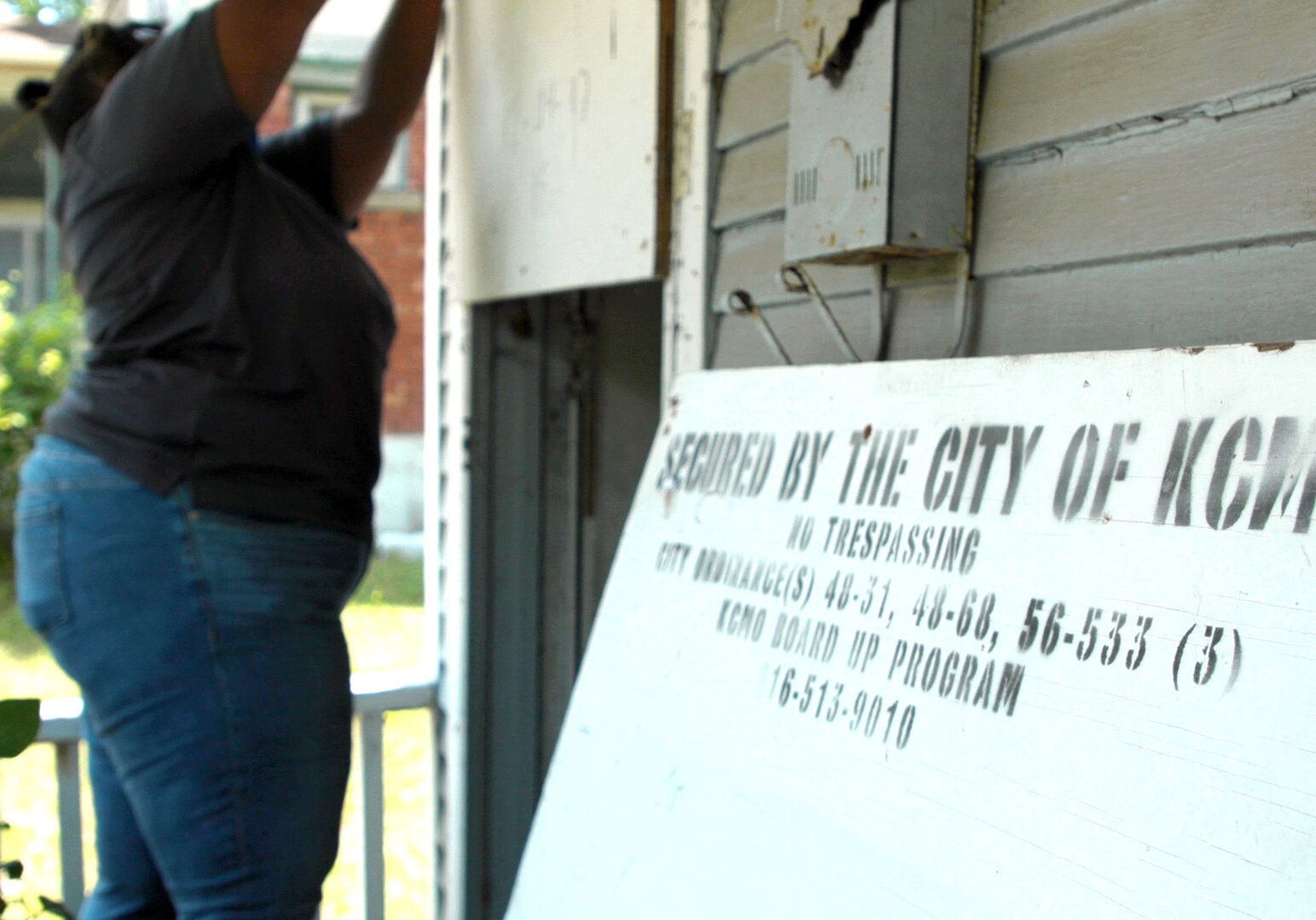 code enforcement officer DeJuan Carpenter removes screws from the piece of wood blocking entry to 2404 Monroe Ave., a vacant home in the Land Bank Program. (Cody Boston | Flatland)
