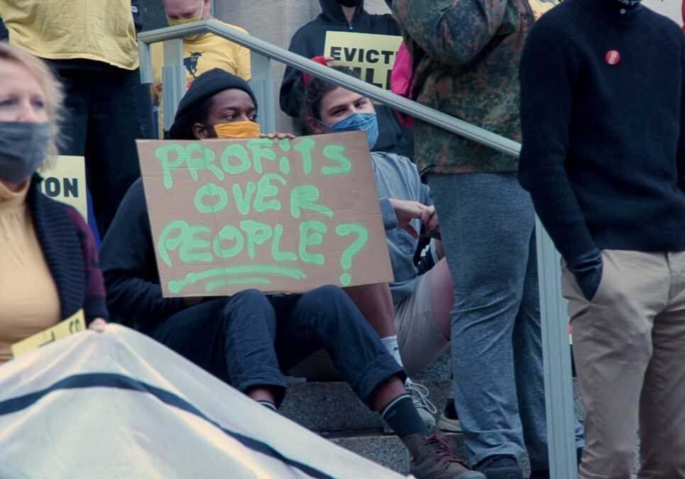 A protester holds a sign that says "People Over Profits" during a demonstration against eviction.