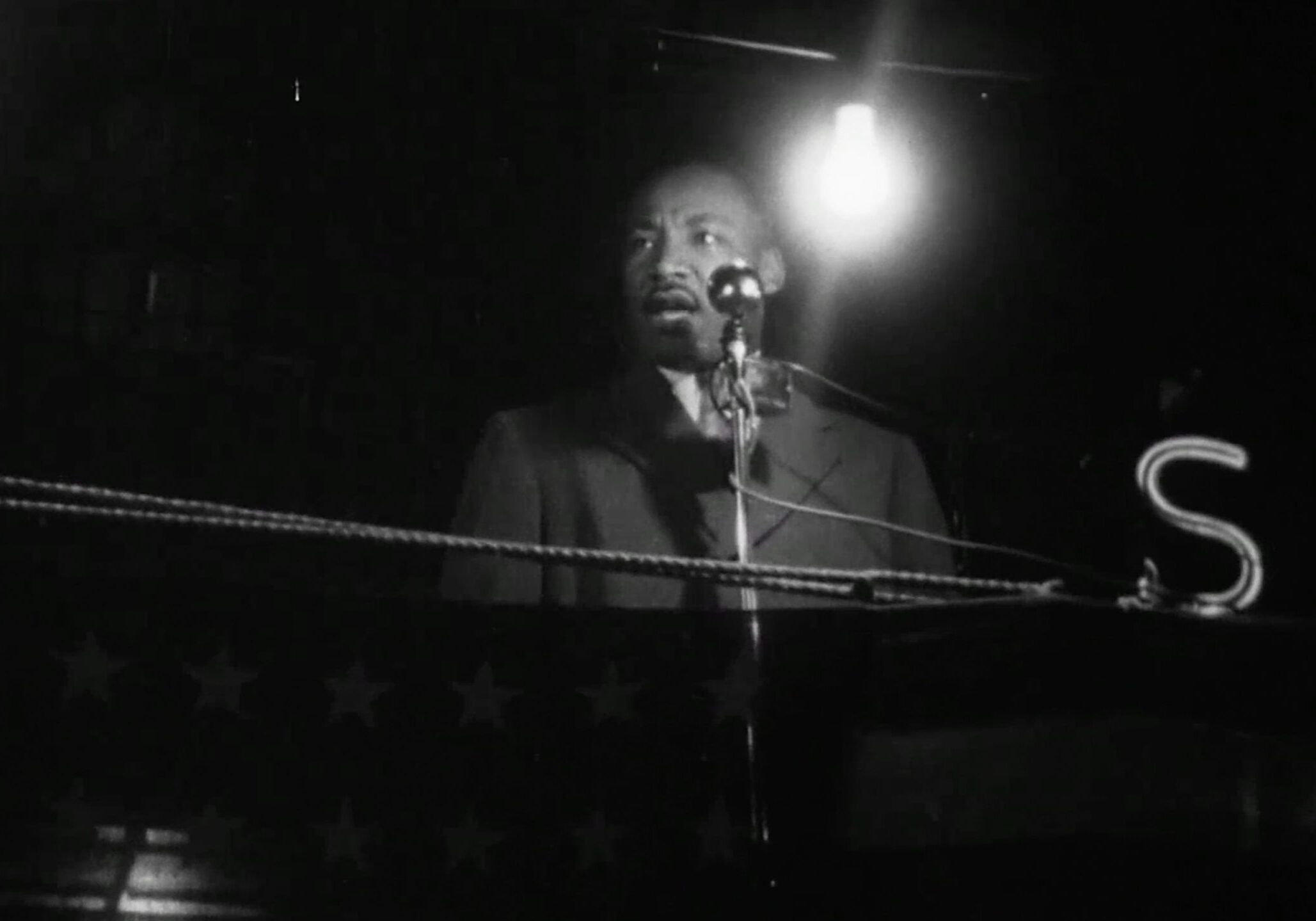 Martin Luther Jr. stands at a pulpit, with a light shining behind him. Jr. was a speaker at the Mammoth Rally on May 3 in the late 1950s.