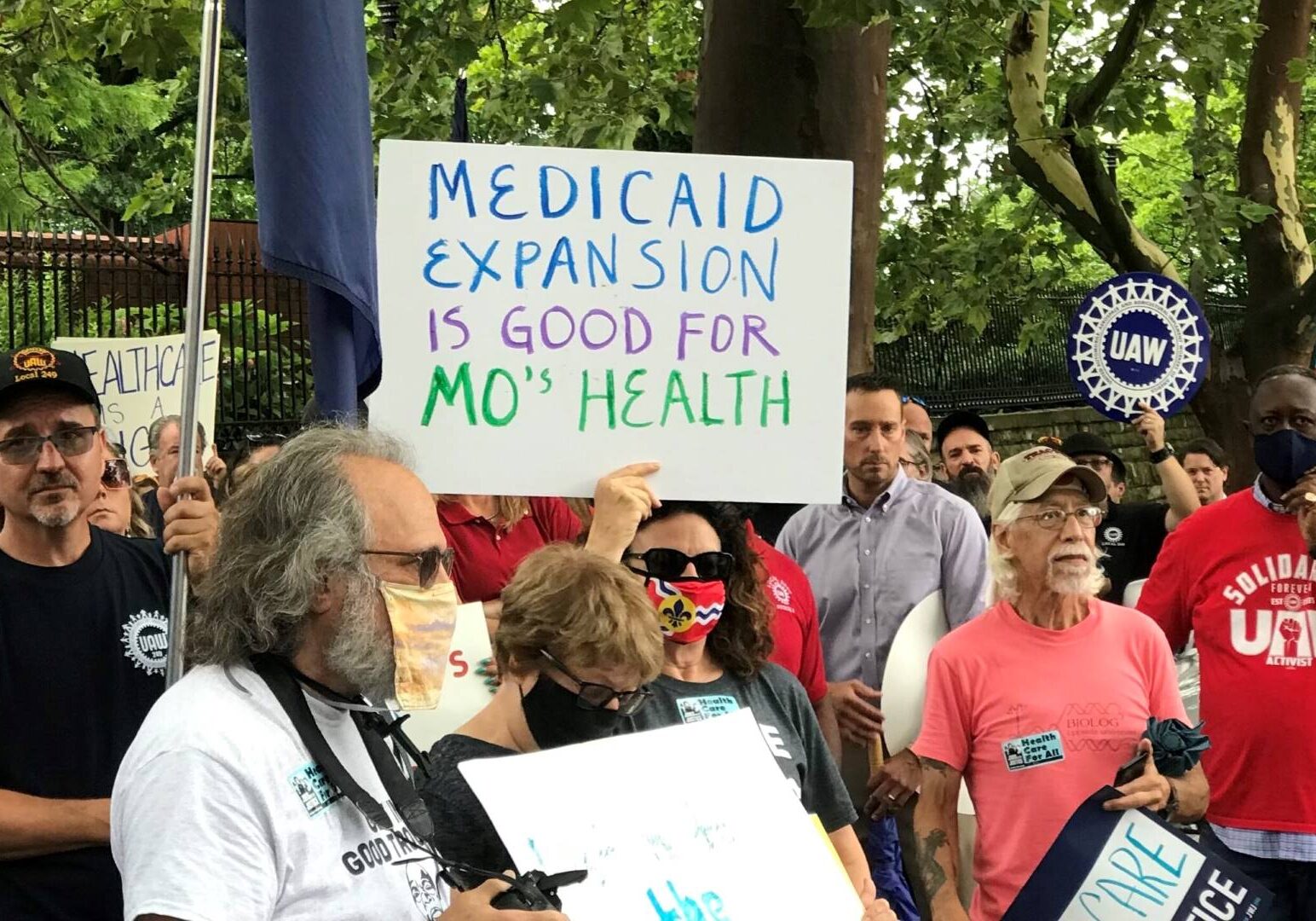 Demonstrators stand outside of the Governor's Mansion in Jefferson City on July 1, 2021 and hold signs urging Gov. Mike Parson to fund voter-approved Medicaid expansion.