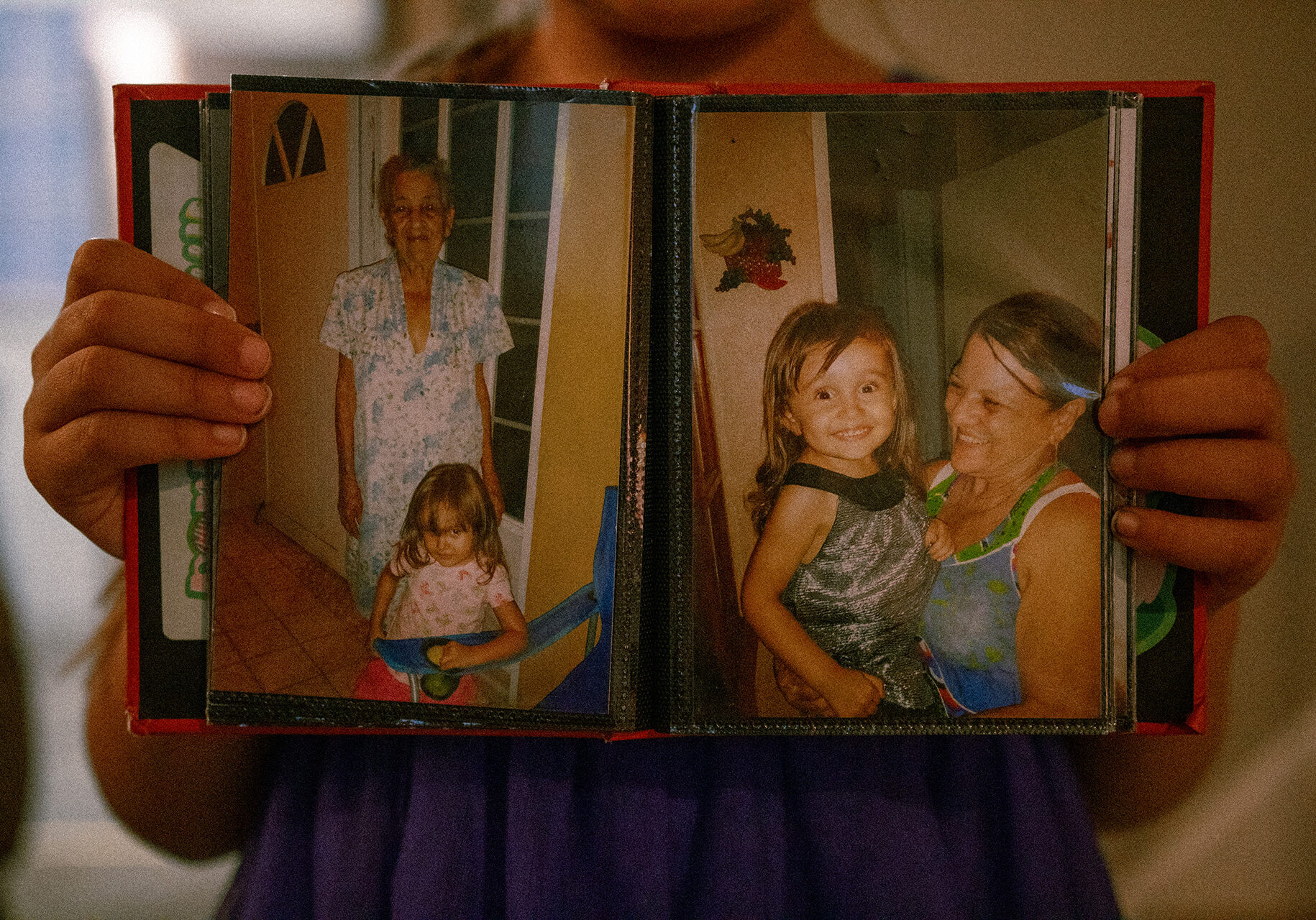 A photo album held by an eight year old's hands, displaying photos of her grandmother and great-grandmother. At the time, she and her parents were living in Puerto Rico. They moved to Kansas after hurricane Maria. ( Ji Stribling | Flatland)