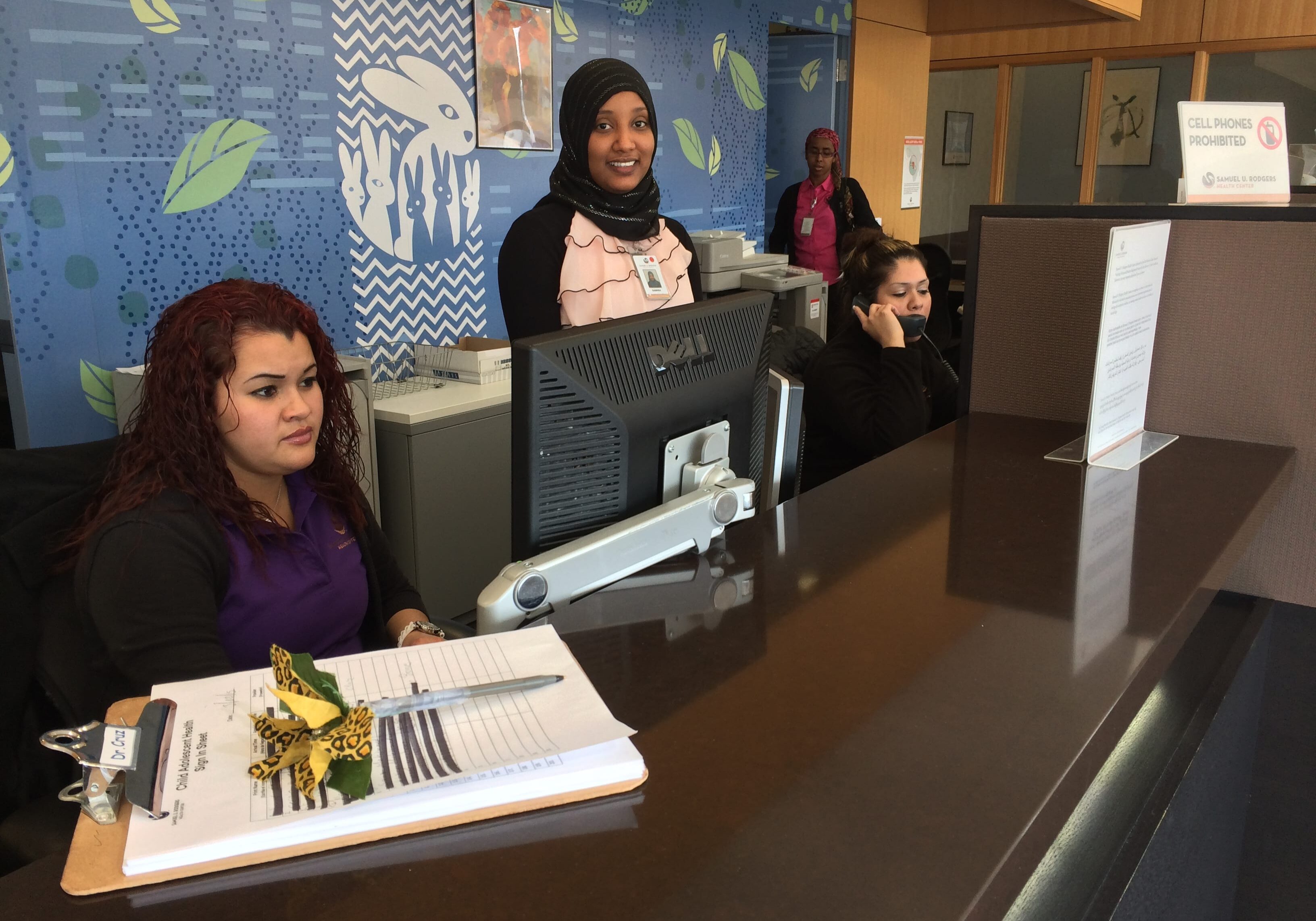 Iris Ulloa, left, Samira Jeylani, center, and Vanessa Rios, on the phone, work at Samuel U. Rodgers Health Center.
(Photo: Alex Smith / Heartland Health Monitor)