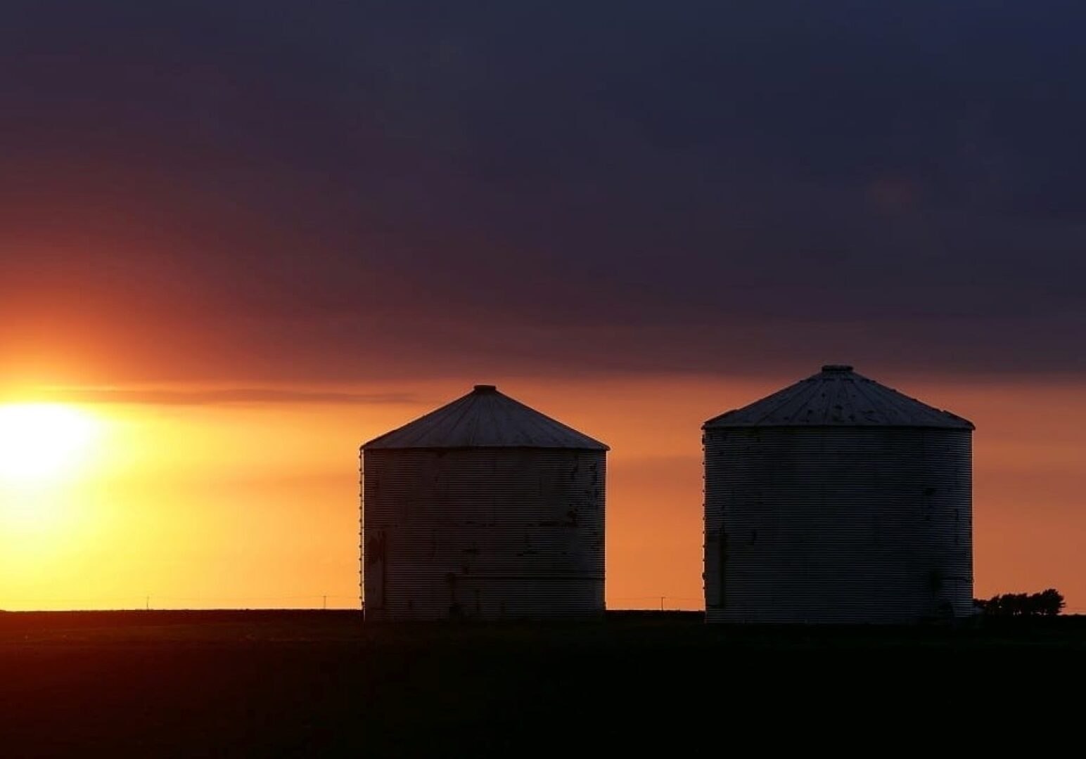 Storm clouds form over grain bins.