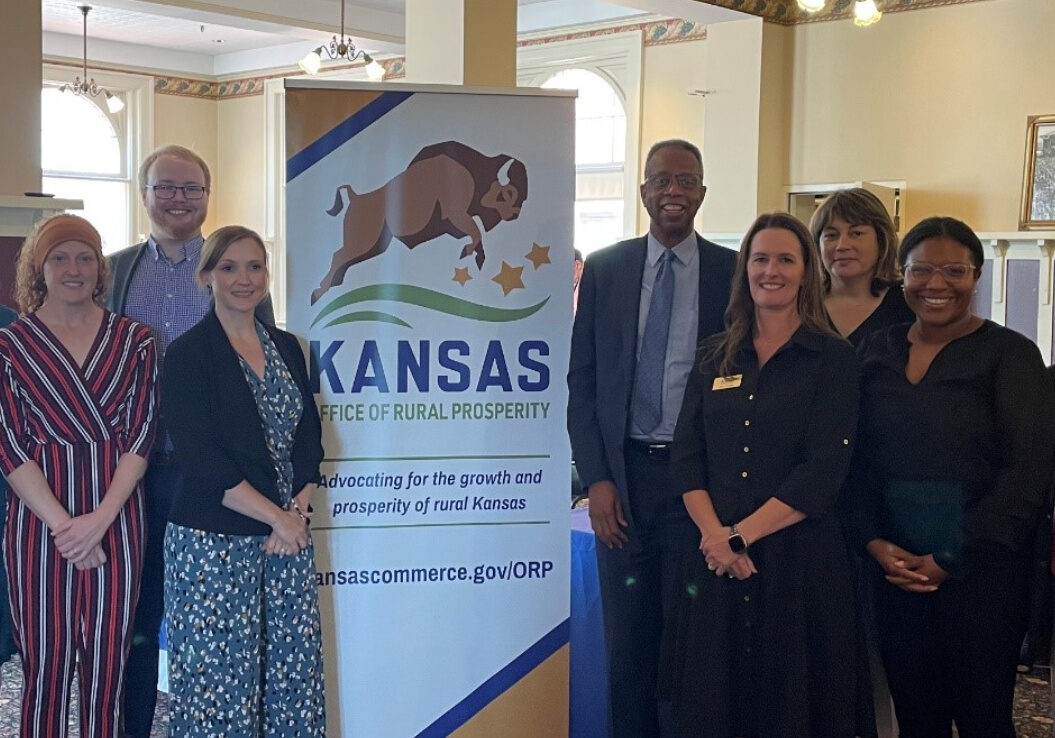 A group of people stand next to a sign with a buffalo that reads "Kansas Office of Rural Prosperity"