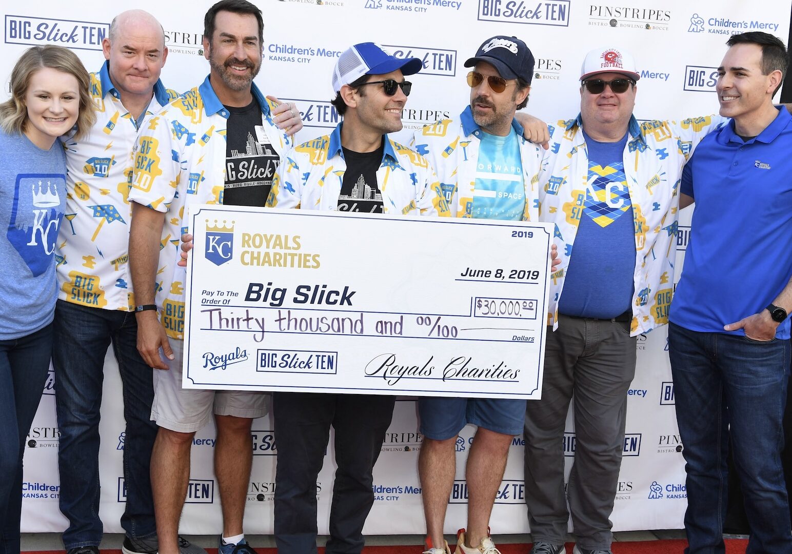 David Koechner, Rob Riggle, Paul Rudd, Jason Sudeikis, and Eric Stonestreet pose with a large check at a past Big Slick Weekend.
