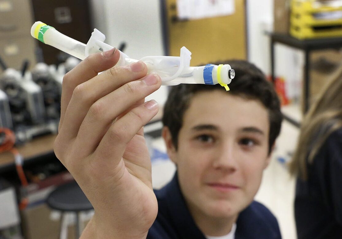 Photo of student holding up small plastic tube.