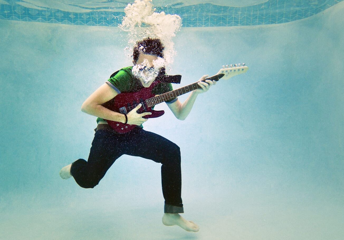 a teenager playing a guitar underwater