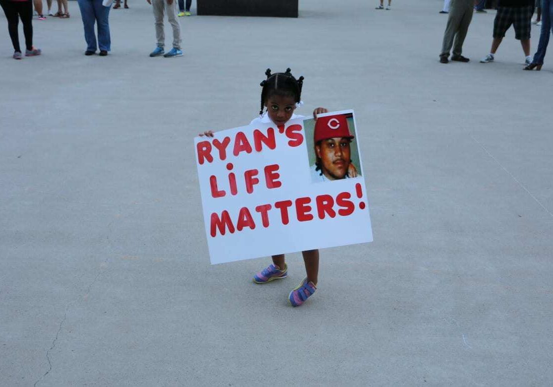 Neriha Stokes, the daughter of Ryan Stokes holding sign at vigil that says Ryan's Life Matters