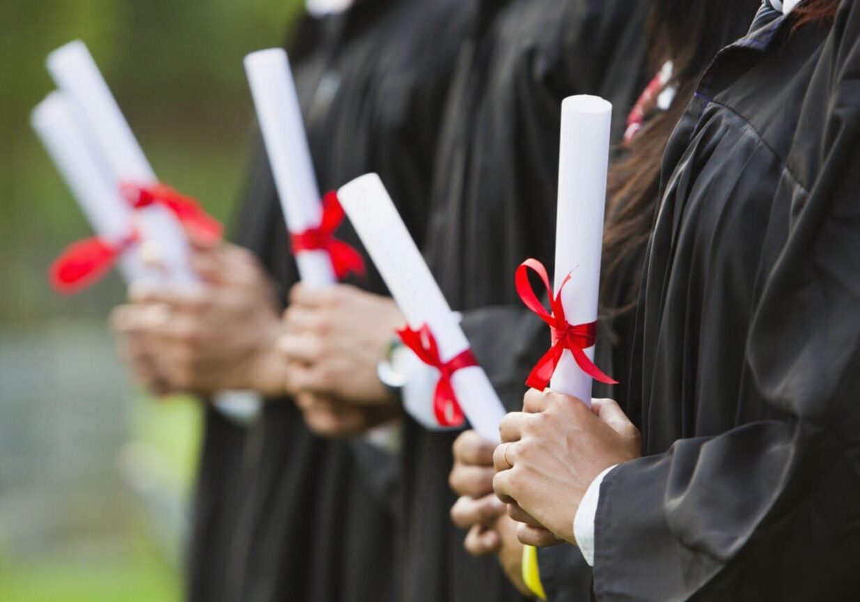 College students holding diplomas at graduation ceremonies.
