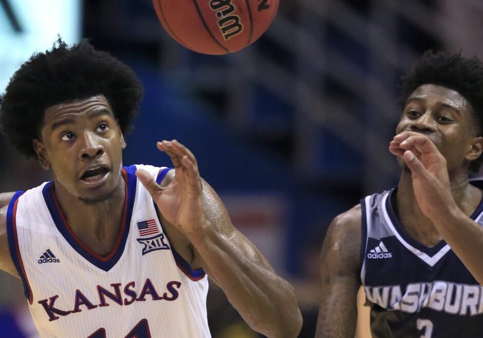 Two basketball players running for the ball.