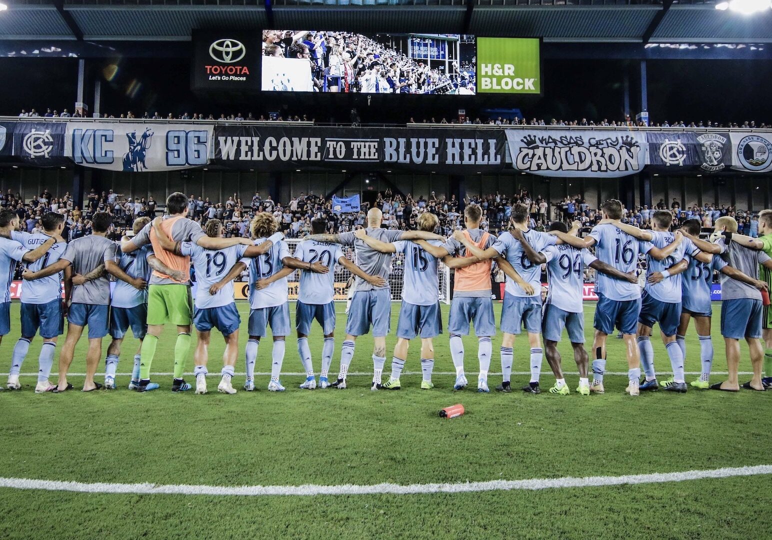 The Sporting Kansas City soccer team lines up and locks arms in front of the home crowd