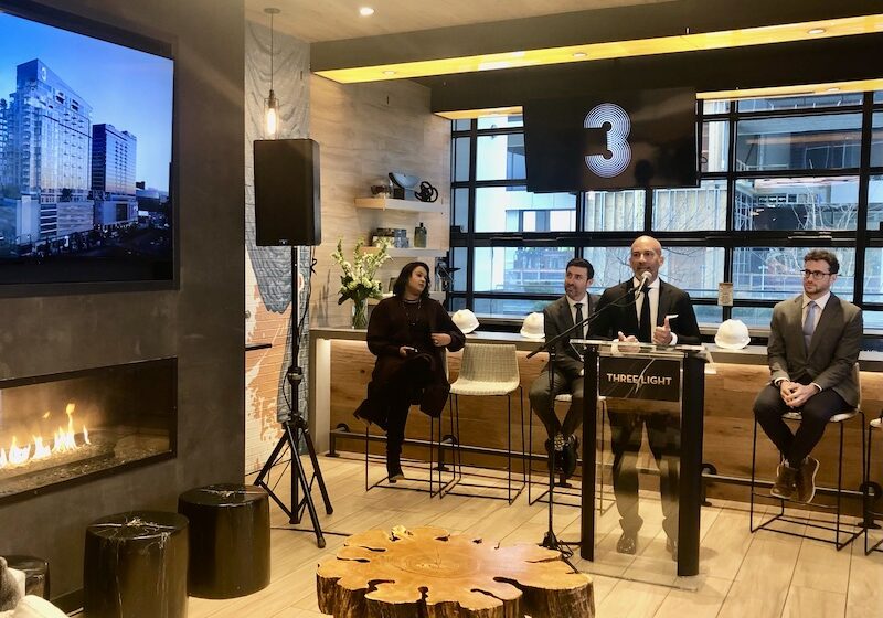 John Moncke, president of the Power & Light District, speaks at the Three Light topping off event, City Manager Brian Platt is seated to his left, City Councilman Eric Bunch to his right.