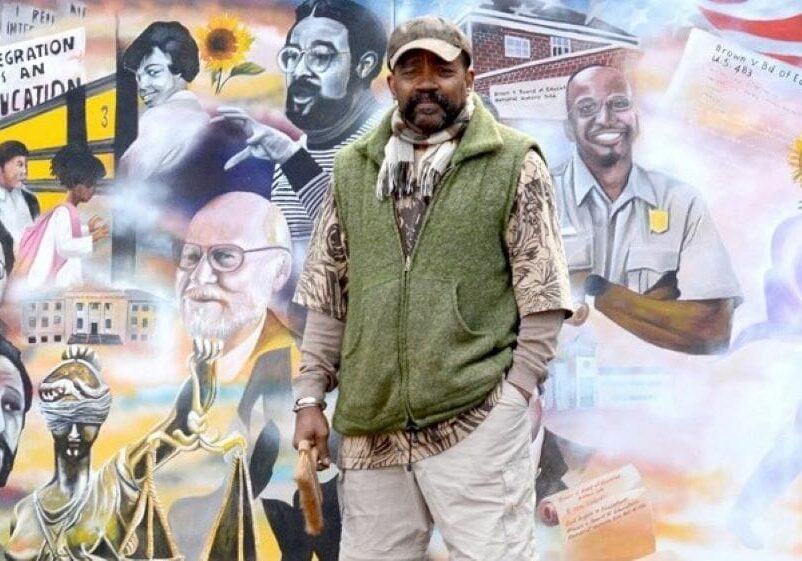 Artist Michael Toombs in front of a mural commemorating the Brown v. Board of Education ruling.